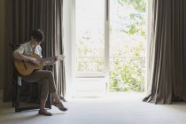 Mulher tocando guitarra dentro de casa — Fotografia de Stock