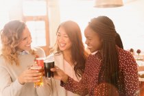 Freundinnen stoßen in Bar auf Biergläser an — Stockfoto