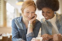 Женщины вместе пользуются мобильным телефоном в кафе — стоковое фото