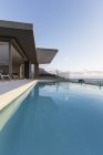 Tranquila piscina de regazo azul fuera de la moderna casa de lujo escaparate exterior - foto de stock