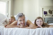 Отец и дети отдыхают на кровати — стоковое фото