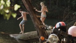 Junges Paar auf Baumstamm am Seeufer — Stockfoto