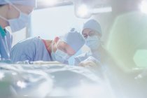 Cirurgião masculino focado realizando cirurgia em paciente do sexo feminino na sala de cirurgia — Fotografia de Stock