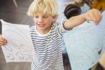 Student showing off drawings in classroom — Stock Photo