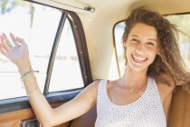 Woman feeling breeze from backseat car window — Stock Photo