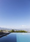 Транквіль розкішний нескінченний басейн з видом на гори під сонячним блакитним небом — стокове фото