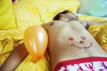 Homem com rosto sorridente desenho na barriga dormindo após a festa — Fotografia de Stock