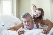 Pai e filhos brincando na cama — Fotografia de Stock
