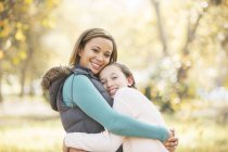 Retrato de madre e hija sonrientes abrazándose al aire libre - foto de stock