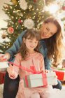 Mãe ajudando filha abrir presente de Natal — Fotografia de Stock