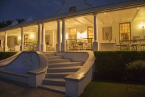 Роскошный дом с верандой, освещённой ночью — стоковое фото