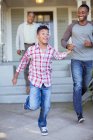 Vater und Sohn halten sich an Händen und rennen vor Haus — Stockfoto