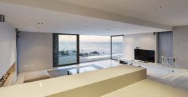 Sala de estar de luxo moderna e minimalista com portas de pátio abertas à vista para o mar — Fotografia de Stock