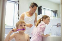 Père et enfants se brossant les dents dans la salle de bain — Photo de stock