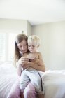 Діти використовують мобільний телефон разом на ліжку — стокове фото