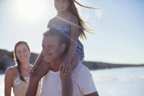 Батько тримає дочку на плечах на пляжі — стокове фото