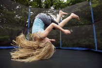 Girl jumping on trampoline outdoors — Stock Photo