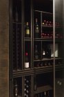 Wine bottles organized on wooden shelves in wine library — Stock Photo