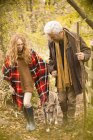 Couple avec chien et bâton de marche dans les bois d'automne — Photo de stock