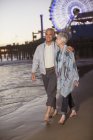 Senior couple walking on beach at sunset — Stock Photo