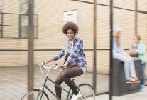 Счастливая молодая женщина на велосипеде по городской улице — стоковое фото
