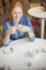 Femme dégustant une tasse de café dans un café — Photo de stock