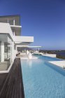 Sunny, tranquille maison de luxe moderne vitrine extérieure avec piscine à débordement — Photo de stock