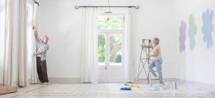 Older couple hanging curtains together — Stock Photo