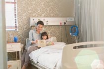Mãe leitura livro com menina filha no quarto do hospital — Fotografia de Stock