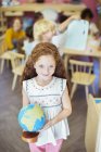 Student holding globe in classroom — Stock Photo