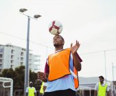 Футболист держит мяч на голове — стоковое фото