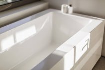 Солнечные размышления над современной белой ванной — стоковое фото