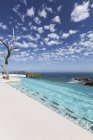 Nuages dans le ciel bleu sur la piscine de luxe surplombant l'océan — Photo de stock