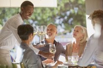 Waiter serving white wine to couples at restaurant table — Stock Photo