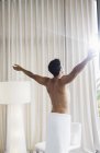 Uomo in asciugamano crogiolarsi alla luce del sole alla finestra — Foto stock