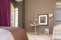 Mesa auxiliar y pintura en dormitorio moderno - foto de stock