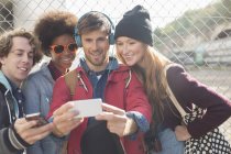 Friends taking self-portrait with camera phone outdoors — Stock Photo