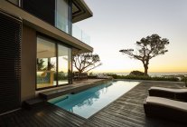 Modern luxury home showcase patio and swimming pool with sunset ocean view — Stock Photo