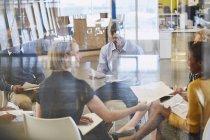 Empresários revisando papelada em reunião no escritório moderno — Fotografia de Stock