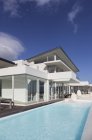 Maison de luxe moderne ensoleillée et tranquille vitrine extérieure avec piscine sous ciel bleu — Photo de stock