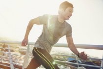 Решительный бегун, бегущий по солнечному пешеходному мосту — стоковое фото