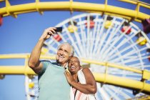 Coppia anziana scattare selfie al parco divertimenti — Foto stock