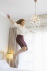 Businesswoman jumping on bed in hotel room — Stock Photo