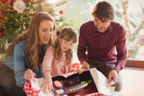 Родители смотрят, как дочь открывает рождественский подарок — стоковое фото