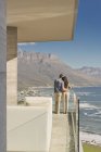 Casal olhando para o mar ensolarado e vista para a montanha a partir de varanda de luxo — Fotografia de Stock
