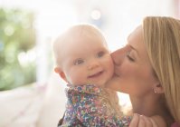 Mutter küsst Baby-Mädchen die Wange — Stockfoto