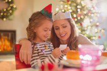 Mutter und Tochter tragen Papierkronen am Weihnachtstisch — Stockfoto