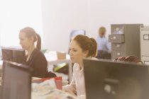 Mulheres de negócios focalizadas que trabalham em computadores no escritório — Fotografia de Stock