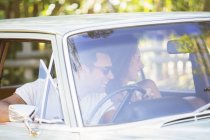 Пара, насолоджуючись їздою на машині в сонячний день — стокове фото