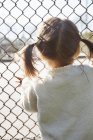 Menina de pé na cerca do elo da cadeia — Fotografia de Stock